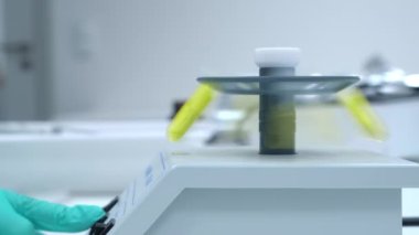 Laboratuvar çalışanı el, numunelerin mikro santrifüj kullanılarak karıştırılması için başlangıç düğmesine basar.