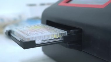 Mikro plaka okuyucusunun otomatik açılışı ve mikro plakayı alan bilim adamı. 