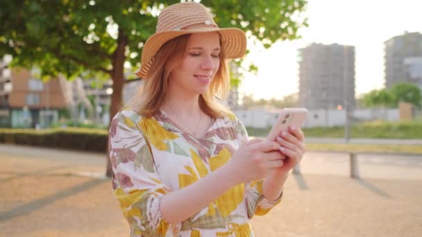 Szczęśliwa Kobieta Słomkowym Kapeluszu Kwiecistej Sukience Stojąca Smartfonem Ulicy — Wideo stockowe