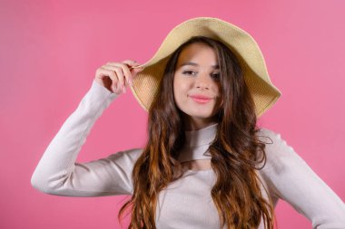 Pembe arka planda hasır şapkalı güzel bir kadın.. 