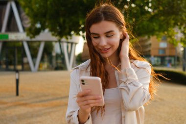 Kızıl saçlı bir kız sokakta dikiliyor ve bir mesaj yazıyor.. 