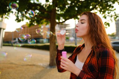 Genç bir kadın sokakta sabun köpüğü üflerken eğleniyor.. 