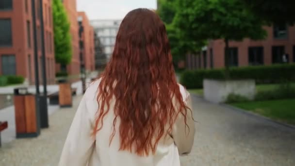 Μια Όμορφη Κοκκινομάλλα Γυναίκα Που Περπατάει Στο Δρόμο Γυρίζει Και — Αρχείο Βίντεο