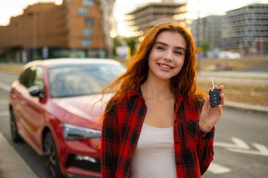 Heyecanlı genç kız arabanın anahtarlarını sokakta gösteriyor.