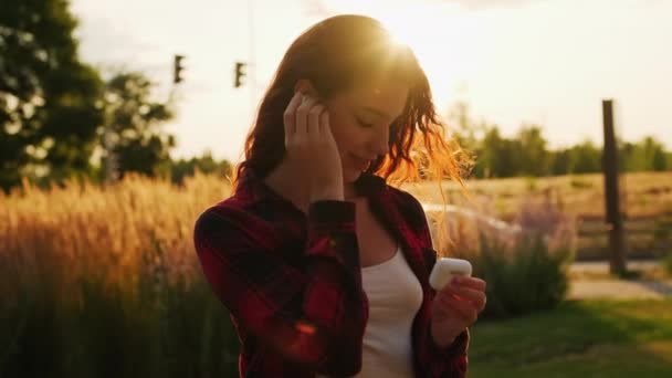 Kulaklığını Kontrol Eden Gün Işığında Müzik Dinleyen Genç Bir Kadın — Stok video