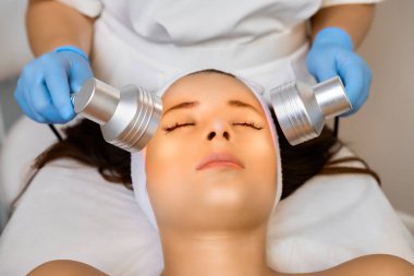 Kozmetik kliniğinde ışık terapisi için donanım kullanan kadın portresi.
