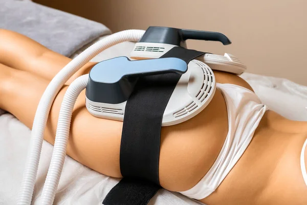 For precise body sculpting, dedicated equipment is positioned on the buttocks of a young woman.