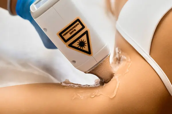 Beautician uses epilation laser treatment to woman armpit, close up.