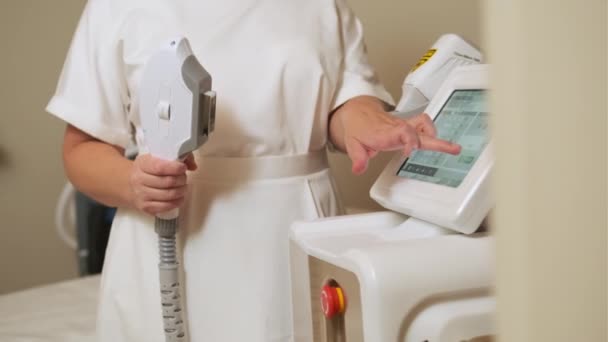 Dermatologen Står Med Utstyr Laser Hårfjerningsanordning Kosmetolog Justerer Enhetsinnstillingene Laser – stockvideo