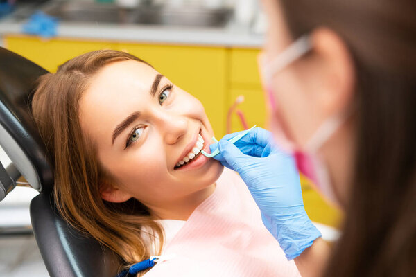 A dentist instructs a young woman on the correct technique for using dental floss