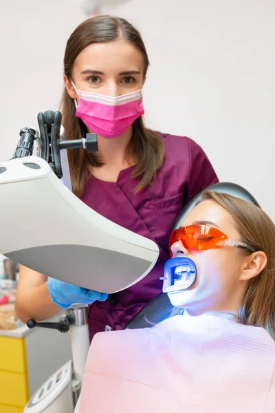 Młody Dentysta Wykonuje Wybielanie Zębów Przy Użyciu Lampy Dla Kobiety — Zdjęcie stockowe