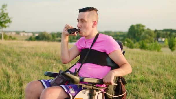 핑크색 티셔츠 연기를 휠체어에 장애를 담배를 사용하는 사람은 햇빛에 초원을보고 — 비디오