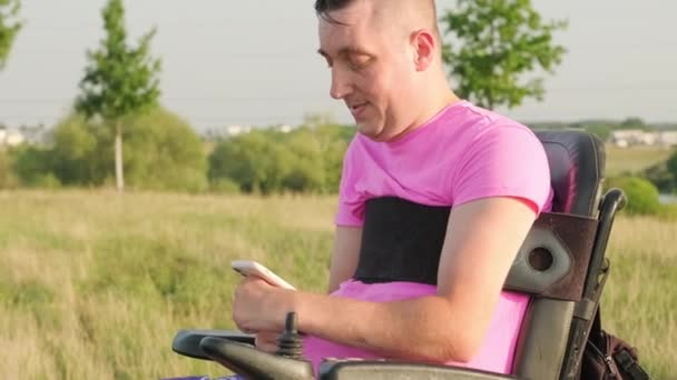 Dojrzały Mężczyzna Wózku Inwalidzkim Trzyma Smartfona Rannych Pięściach Łące Krajobraz — Wideo stockowe