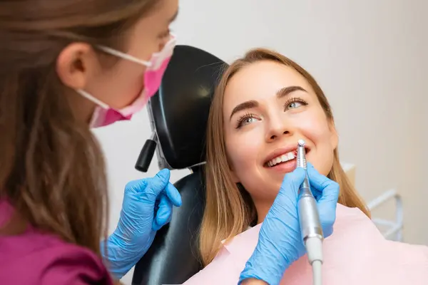 Dentist doing procedure of teeth grinding in dental clinic. Woman visits dentist practitioner creating perfect smiles by grinding procedures