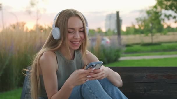 Lächelnde Junge Frau Hört Musik Auf Bank Park Sitzend Fröhliche — Stockvideo