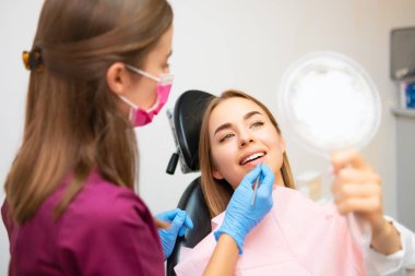 Çekici kadın dişlerini tedavi ettikten sonra güzel gülüşünü aynada kontrol ediyor.