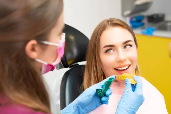 stock image Dentist picks out plastic molds to create dental impressions to make orthodontic alignments. 