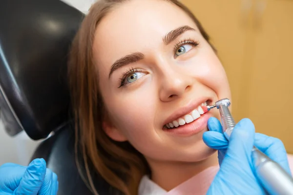 Woman patient sitting in medical chair during teeth grinding procedure.