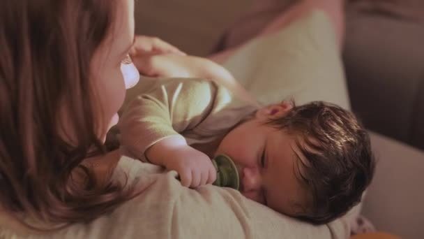 Moeder Glimlacht Terwijl Baby Haar Armen Houdt Zuigeling Zuigt Fopspeen — Stockvideo