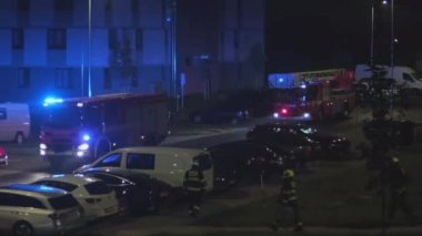 Prag sokaklarındaki itfaiye araçları ve itfaiyeciler uyarı ışıklarını yaktılar. Gece ve araçlar şehrin yerleşim bölgesinde.