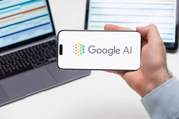Google AI logosu, arka planda grafiksel diyagramlı tablet ve dizüstü bilgisayarlı akıllı telefonun ekranında, Aralık 2023, Prag, Çek Cumhuriyeti.