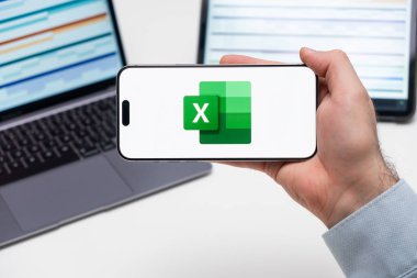 Bilgisayarlı akıllı telefon ekranında Excel logosu ve arka planda grafiksel diyagramlar olan tablet, Aralık 2023, Prag, Çek Cumhuriyeti.