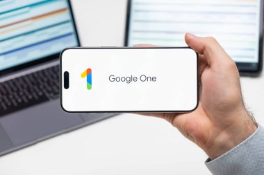 Google Bir uygulama logosu cep telefonu ekranında laptopun ve tabletin önünde duran adam tarafından, Aralık 2023, Prag, Çek Cumhuriyeti