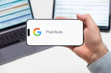 Bilgisayarın ve tabletin önündeki adamın cep telefonu ekranındaki uygulamanın Piksel Buds logosu, Aralık 2023, Prag, Çek Cumhuriyeti