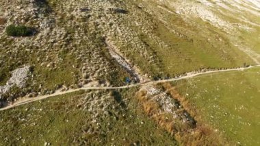 Yürüyüşçü, ünlü Tre Cime di Lavaredo yakınlarındaki İtalyan Alpleri 'nin uçsuz bucaksız çayırlarında dolambaçlı bir patikada yol alır..