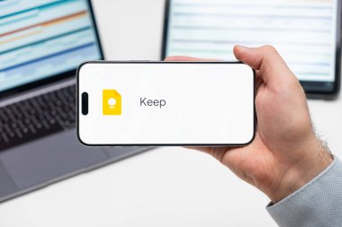 Uygulamanın logosunu bilgisayarın ve tabletin önündeki adamın cep telefonu ekranında tut, Aralık 2023, Prag, Çek Cumhuriyeti