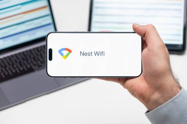 Uygulamanın Wifi logosu cep telefonu ekranında laptopun ve tabletin önünde duran adamın elinde, Aralık 2023, Prag, Çek Cumhuriyeti