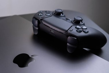 BERLİN, GERMANY - 14 HAZİRAN 2024: Bir Apple MacBook Pro Space Black üzerinde oyun oynamak için tasarlanmış DualSense denetleyicisinin ayrıntılı bir görüntüsü.