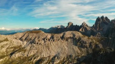 Batan güneşin sıcacık parıltısı Tre Cime di Lavaredo 'nun ikonik sivri tepelerini yıkıyor. İtalyan Alplerinin dramatik manzarasını vurguluyor..