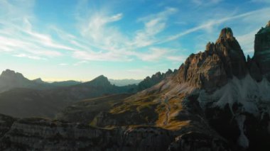 Batan güneş, Tre Cime di Lavaredo 'nun yüksek tepelerine sıcak bir ışık saçıyor. İtalyan Alplerinin engebeli güzelliğini vurguluyor..
