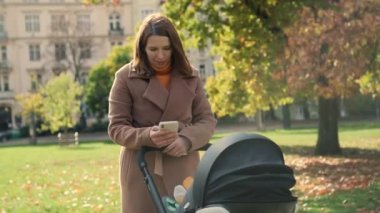Bayan, hafızasını korumak için bebek arabasındaki çocuğun resmini çekiyor. Kadın, çocuk yürürken kocasının mesajlarına cevap verir.