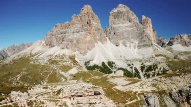 Yürüyüşçüler, ikonik Tre Cime di Lavaredo dağ sırasına bakan bir tepenin üzerindeki İtalyan Alplerinin tadını çıkarın..
