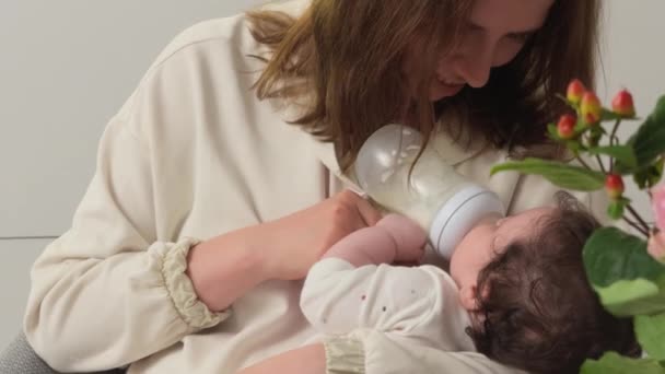 妈妈用一个小婴儿瓶喂女婴 温柔地看着女儿 — 图库视频影像