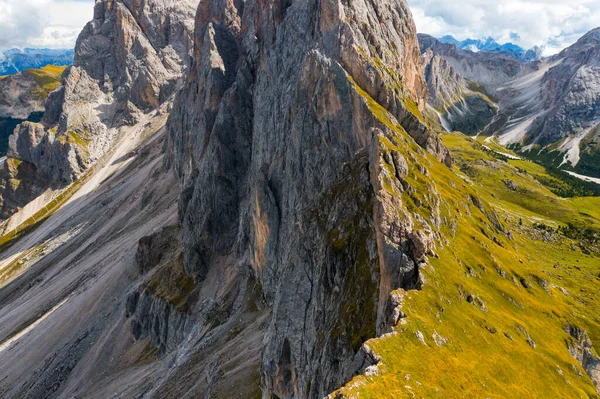 stock image Rocky Seceda mountain range slope covered with fresh green grass in shadow. Scenic wild nature of Italian Alps on sunny summer day aerial view