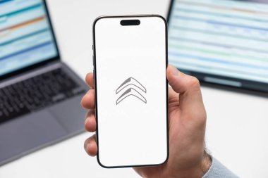 PRAG, CZECHIA - Şubat 2024: Citroen otomobil logosu arka planda erkek eli ve dizüstü bilgisayarda akıllı telefon ekranında 