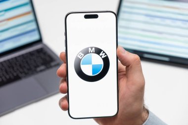 PRAG, CZECHIA - Şubat 2024: BMW otomobil logosu arka planda erkek eli ve dizüstü bilgisayarda akıllı telefon ekranında 