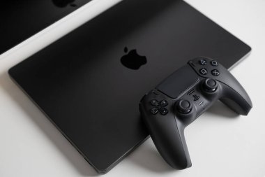 BERLİN, ALMANY - 14 Şubat 2024: Masadaki MacBook Pro 'nun yanındaki oyun denetleyicisi.