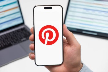 PRAG, CZECH REPUBLIC - 21 Ocak 2024: Pinterest logosu erkek elinin iş arka planında yer alan akıllı telefon ekranında. 