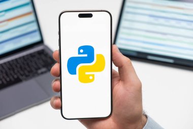 PRAGUE, CZECH REPUBLIC - 21 HAZİRAN 2024: İş arka planındaki erkek eli akıllı telefon ekranında Python logosu. 
