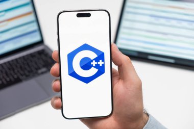 PRAG, CZECH REPUBLIC - HAZİRAN 21: 2024: İşyeri arka planında erkek eli akıllı telefon ekranında C logosu. 