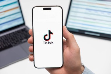 PRAGUE, CZECH REPUBLIC - 21 HAZİRAN 2024: Tiktok logosu, erkeğin iş arka planındaki akıllı telefon ekranında. 