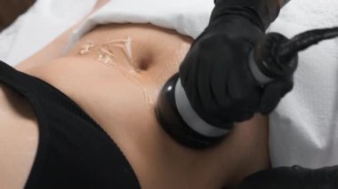 Masör ultrasonik boşluklarla figür düzeltme yapıyor. Spa salonu, göbekte geleneksel liposuction yerine zararsız bir alternatif sunuyor.