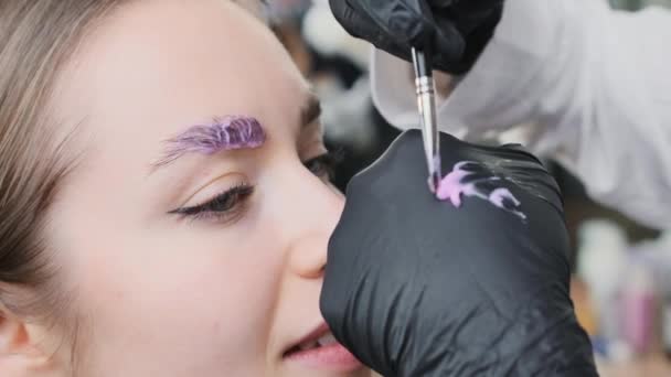 女性在病人眉毛上刷一层肉毒杆菌毒素溶液 在叠层过程中 组件会恢复和加强客户的眉毛 — 图库视频影像