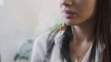 Genç kadın ağzından sigara dumanı salıyor. Çalışmaya ara veren genç bayan için sessiz bir yalnızlık anı.