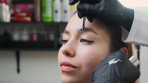 女人在叠层时在病人的眉毛上涂特殊的固定剂 艺术家希望女性的眉毛在手术后保持形态和完整 — 图库视频影像