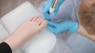 Podolojist klinikteki genç bayana profesyonel tıbbi pedikür yapıyor..